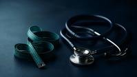 A stethoscope and measuring tape on a dark surface